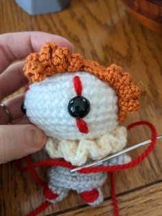 a hand holding a small crocheted doll with scissors in it's hands