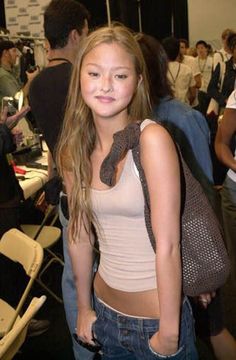 a young woman standing in front of a group of people at a convention or event