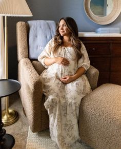 a pregnant woman sitting in a chair next to a lamp