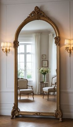 an ornate gold framed mirror in the corner of a room with white walls and wooden floors