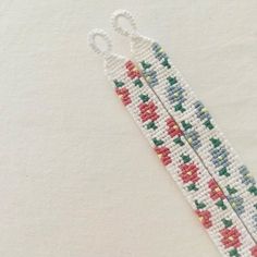 a pair of scissors made out of beaded beads on white paper with red, green and blue flowers