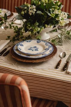 the table is set with plates, silverware and flowers in vases on it