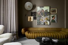 a living room filled with furniture and pictures on the wall next to a window covered in curtains