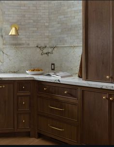 a kitchen with wooden cabinets and marble counter tops, along with a gold light hanging over the sink