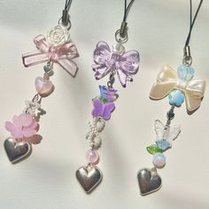 four different colored charms with bows and hearts