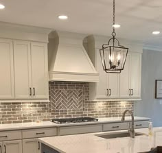 a kitchen with white cabinets and marble counter tops