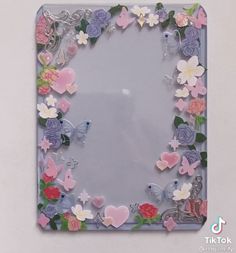 a mirror with flowers and butterflies on it's side, in the shape of a frame