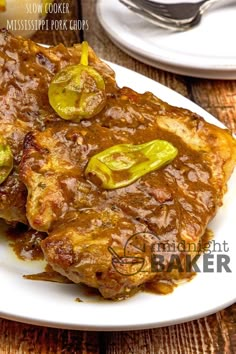 a white plate topped with meat covered in gravy and jalapenos