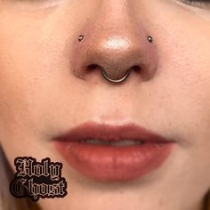 a close up of a woman's nose with piercings on her nose ring