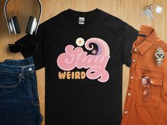 Embrace your unique personality with this 'Stay Weird' graphic tee! Made for those who celebrate their quirks, this shirt is a fun addition to any casual wardrobe. Its comfortable fit and bold design make a statement that's as individual as you are. Perfect for everyday wear, it keeps the positive vibes going whether you're out with friends or just lounging at home. Add a touch of the extraordinary to your style with this unisex fashion top, and enjoy being wonderfully weird. Quirky Girl, Stay Weird, Statement Shirt, Fashion Top, Bold Design, Art Clothes, Tops For Leggings, Casual Wardrobe, Top Casual