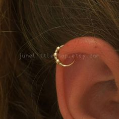 an ear piercing is shown with gold beads