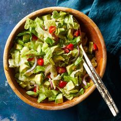 a salad with lettuce, tomatoes and onions in a bowl next to a fork