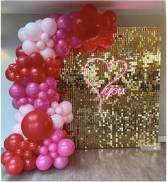 there is a large number of balloons in front of a gold sequin backdrop with the word you on it