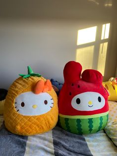 two hello kitty pillows sitting on top of a bed