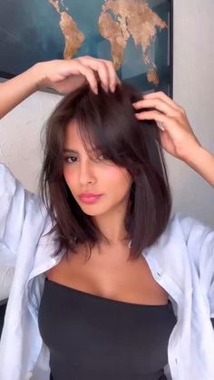 a woman is holding her hair in front of the camera and she is wearing a black top