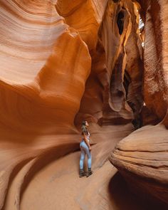 a woman is standing in the middle of a narrow slot between two large rock formations