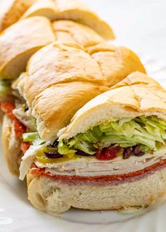 two sub sandwiches sitting on top of a white plate