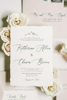 the wedding stationery is laid out on top of each other, with white flowers