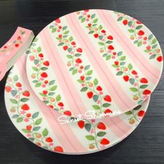 a pink and white plate with red berries on it