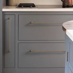 a kitchen with gray cabinets and white counter tops, gold handles on the pulls is shown