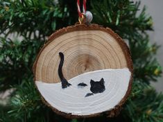 a wooden ornament with two cats on it hanging from a christmas tree branch