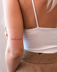 the back of a woman's arm with a small tattoo on her left arm