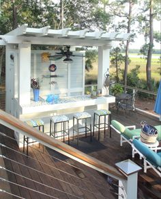 an outdoor bar with chairs and umbrellas on a deck in front of some trees