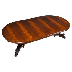 an oval wooden table with carved legs and wood grain on the top, against a white background