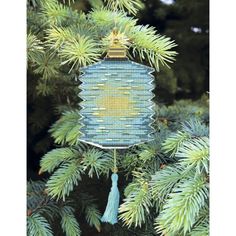 a blue and yellow ornament hanging from a pine tree