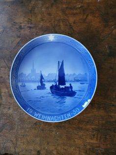 a blue plate with two sailboats on the water in front of a wooden table