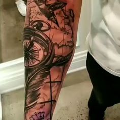 a man's arm with a compass and bird tattoo on it, in front of a mirror