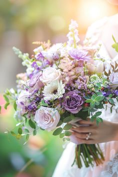 a woman holding a bouquet of flowers in her hands with the sun shining behind her