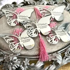 six personalized butterfly spoons with pink tassels on a silver platter