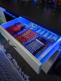 an open drawer with many items in it on a rug next to a counter top