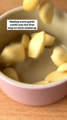 a bowl filled with sliced potatoes on top of a wooden table