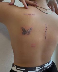 a woman with a butterfly tattoo on her back and the words self love written in cursive writing