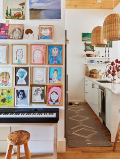 there are many pictures on the wall above the piano in this kitchen and dining room