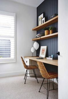 a desk with two chairs in front of it and shelves on the wall behind it