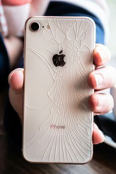 a person holding an iphone in their hand with the screen cracked off and apple logo on it