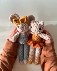 two crocheted stuffed animals are held up by someone's hands in front of them