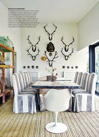 a dining room table with chairs and antlers on the wall