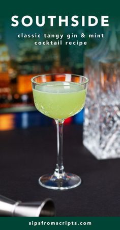 a glass filled with green liquid sitting on top of a table