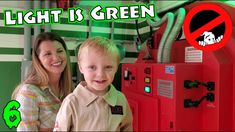 a woman standing next to a boy in front of a machine with the words light is green on it