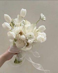 a bouquet of white flowers is being held by someone's hand