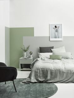 a bedroom with green and white walls, black chairs and a gray bed in the corner