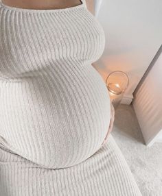 a pregnant woman wearing a white dress and holding a wine glass in her right hand