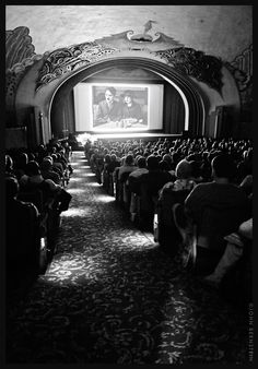 an auditorium with people watching a movie on the screen