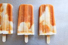 three orange and white popsicles sitting on top of a counter next to each other