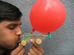 a man blowing on a red balloon with buttons attached to it's head and nose