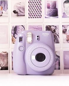 a purple camera sitting on top of a white table next to wall covered with pictures